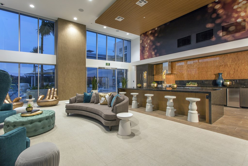 a large living room with couches and a bar and large windows